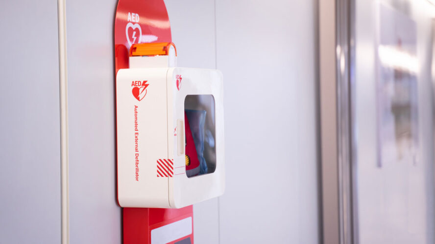 Automatic external defibrillator mounted on white wall.
