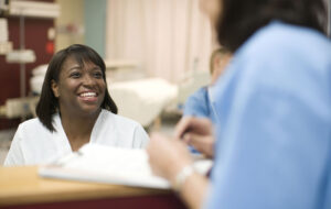 Female nurse talking to doctor at desk in hospital