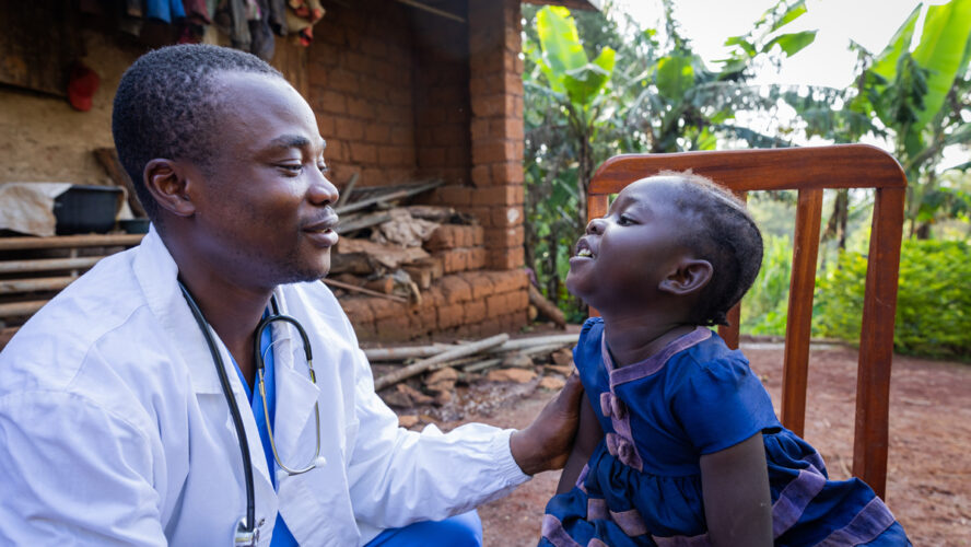 African doctor talking to a sick baby girl during a visit in a rural area in Africa - stock photo