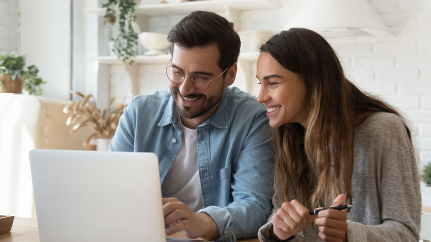 Happy young couple paying bills online in computer app