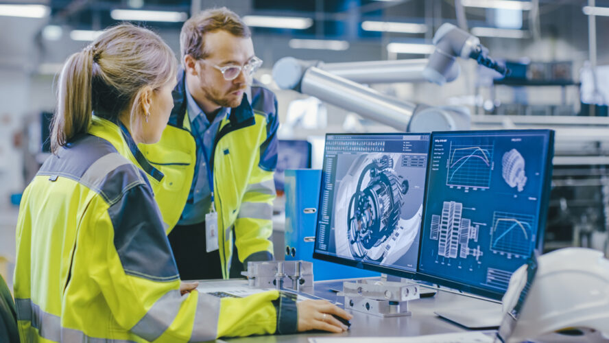 At the Factory: Male Mechanical Engineer Holds Component while Female Chief Engineer Work on Personal Computer, They Discuss Details of the 3D Engine Model Design. - stock photo
