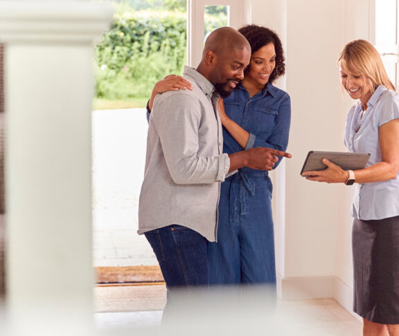 Couple Viewing Potential New Home With Female Real Estate Agent - stock photo