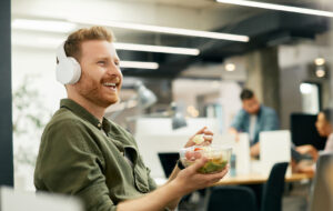 Happy freelance worker listening music while having lunch break at corporate office. - stock photo