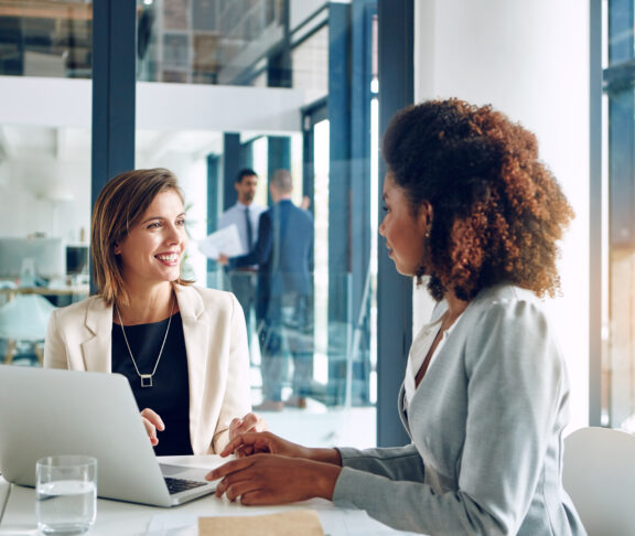 Business people, laptop and women in office for training planning and project idea, research or collaboration. Coaching, support and girl with manager for learning, discussion and problem solving