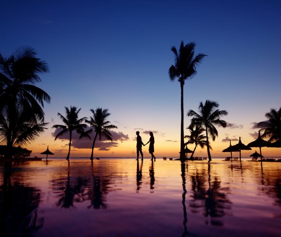 Silhouettes of young couple at scenic sunset on tropical beach