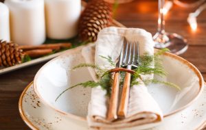 Decorated Thanksgiving or New Year table setting among white candles and winter decor. The concept of a festive dinner.