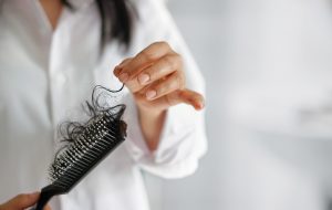 Kvinde med hårbørste fyldt med lange hår