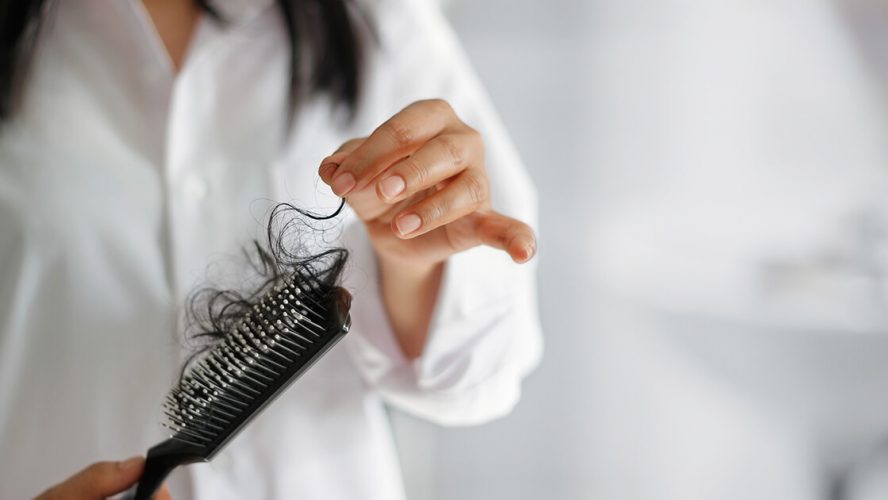 Kvinde med hårbørste fyldt med lange hår