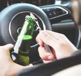 Mand åbner øl, mens han sidder bag rattet i en bil