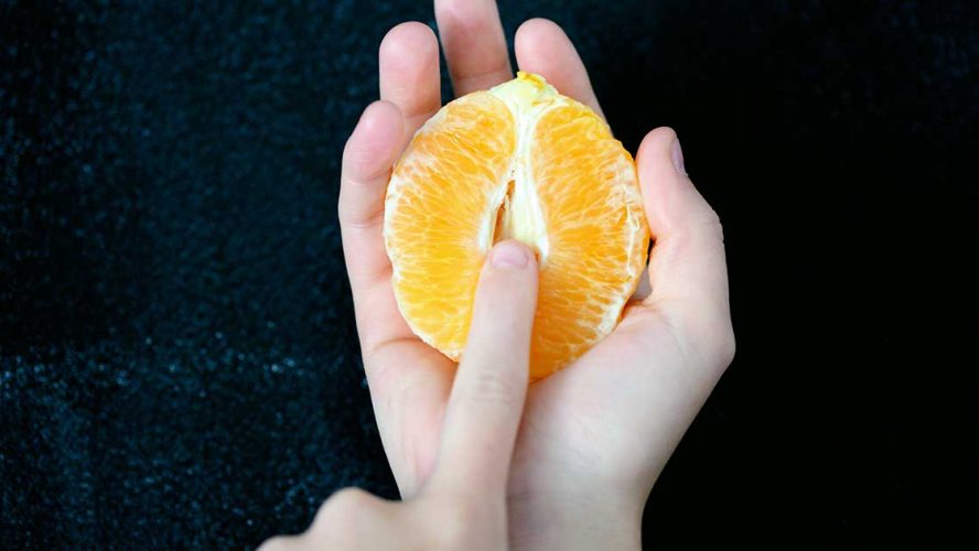 kvinde holder appelsin i hånden, der symboliserer kvindens underliv