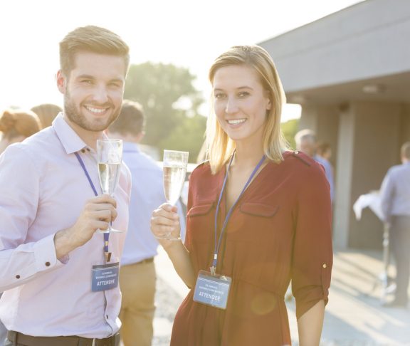 Portrait of smiling young business colleagues standing with wineglasses at rooftop during party