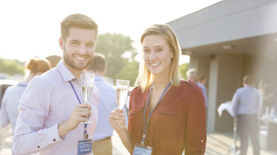 Portrait of smiling young business colleagues standing with wineglasses at rooftop during party