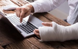 Close-up Of A Businessperson's Hand With Hand Injury Using Laptop