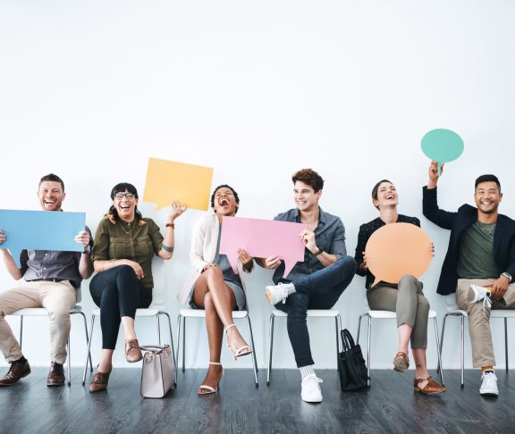Studio shot of a group of businesspeople holding up speech bubbles while they wait in line