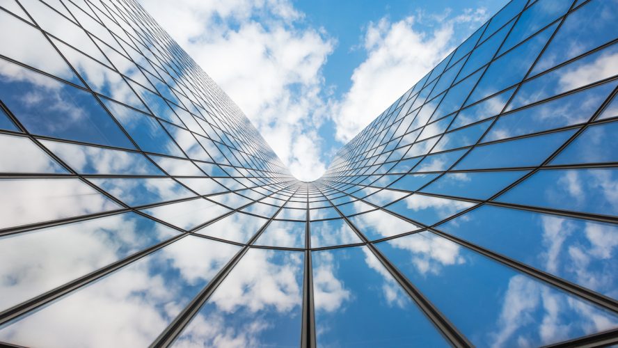 Blue sky and white clouds reflecting in a curved glass building