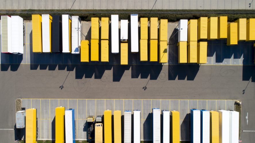 Aerial view of cargo containers, semi trailers, industrial warehouse, storage building and loading docks, Bavaria, Germany