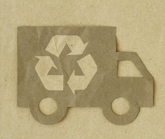 Paper cut of truck with recycling symbol on recycled paper background - Green transportation concept