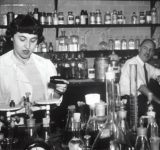 schwarz weiß Bild in einer alter Apotheke, ein Mann und eine Frau abgebildet