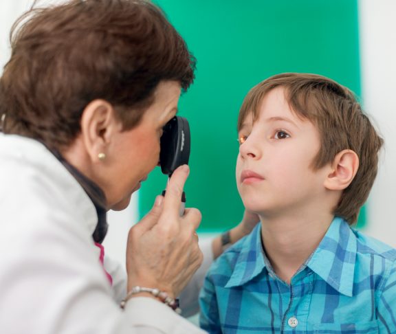 Senior female doctor doing eye test with boy patient