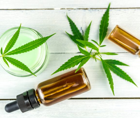 CBD Cannabis Hemp topical cream and oils balm with cannabis leafs on wooden table