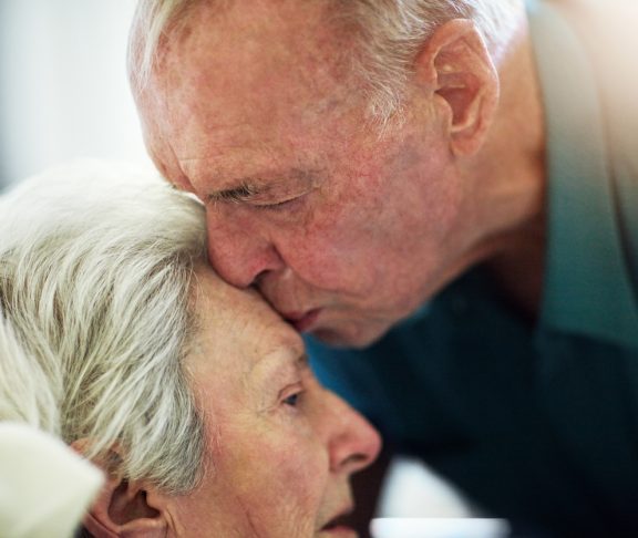 Cropped shot of a senior man kissing his sick wife on the forehead during a hospital visit