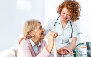 Friendly relationship between smiling caregiver in uniform and happy elderly woman.