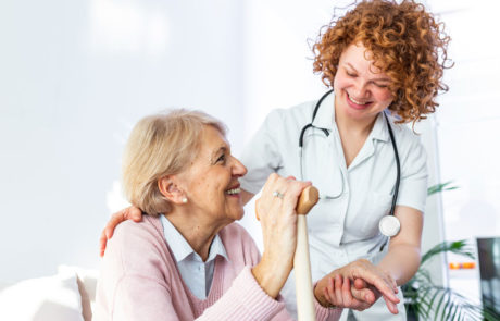 Friendly relationship between smiling caregiver in uniform and happy elderly woman.