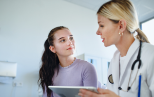 Young woman doctor explaining diagnosis to teenage girl