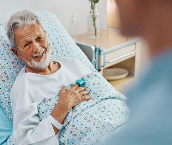 Happy senior patient talking to a nurse while recovering in the hospital ward.
