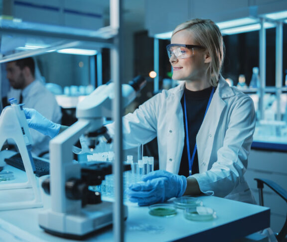 Female Research Scientist Uses Micropipette to Mix Liquids in a Sample Test Tube in a Modern Laboratory. Scientists are Conducting DNA Research with the Help of Technology, Microscopes and Computers