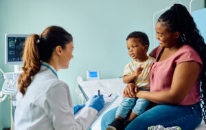 African American boy and his mother talking to female pediatrician at doctor's office.