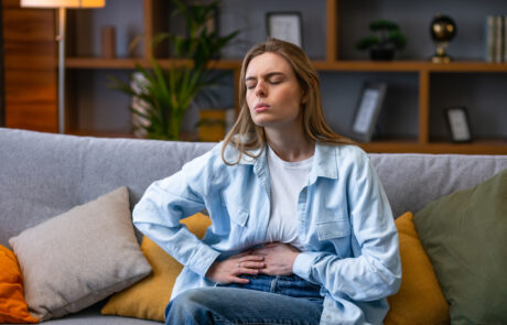 Woman hand in stomach ache, suffer from food poisoning, abdominal pain and colon problem, gastritis. Patient belly, abdomen or inflammation, concept. - stock photo