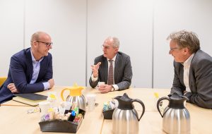 Drie mannen in gesprek aan een vergadertafel
