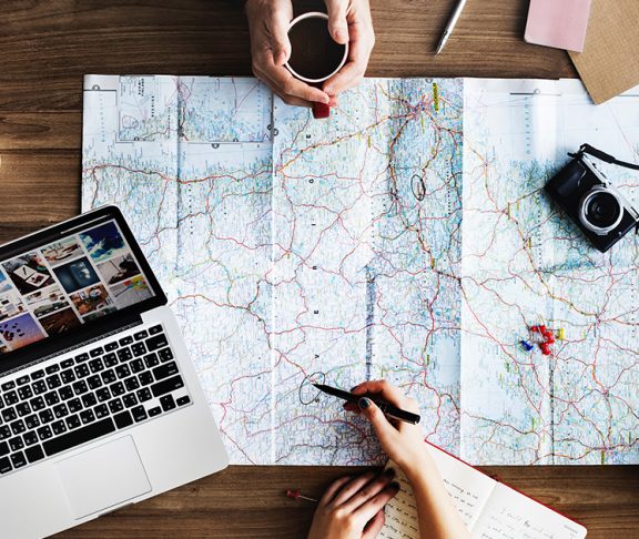 Twee personen plannen reis met landkaart en laptop op houten tafel