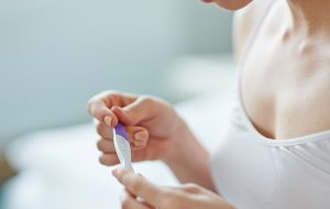 Vrouw zit in badkamer met zwangerschapstest haar handen