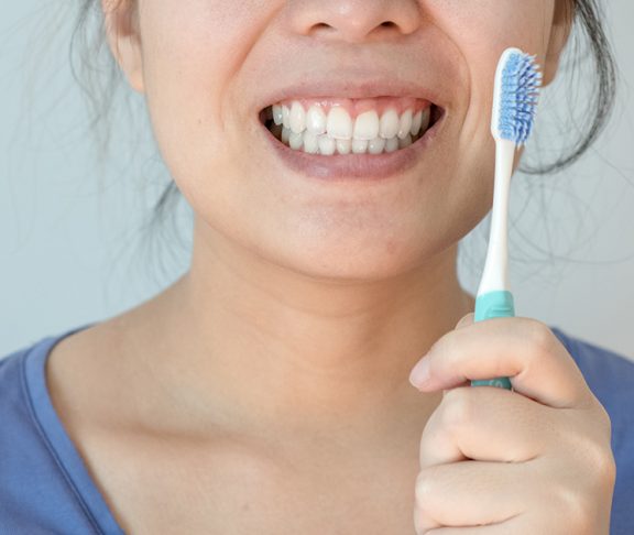 Vrouw toont tanden en tandenborstel