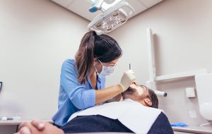 Vrouwelijke tandarts behandelt mannelijke patiënt