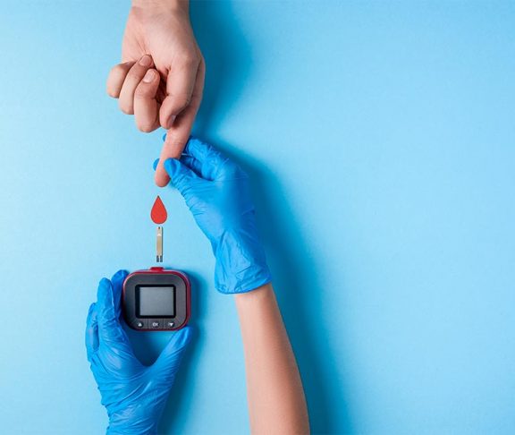 Verpleegster doet bloedtest. Hand met bloeddruppel en glucosemeter.