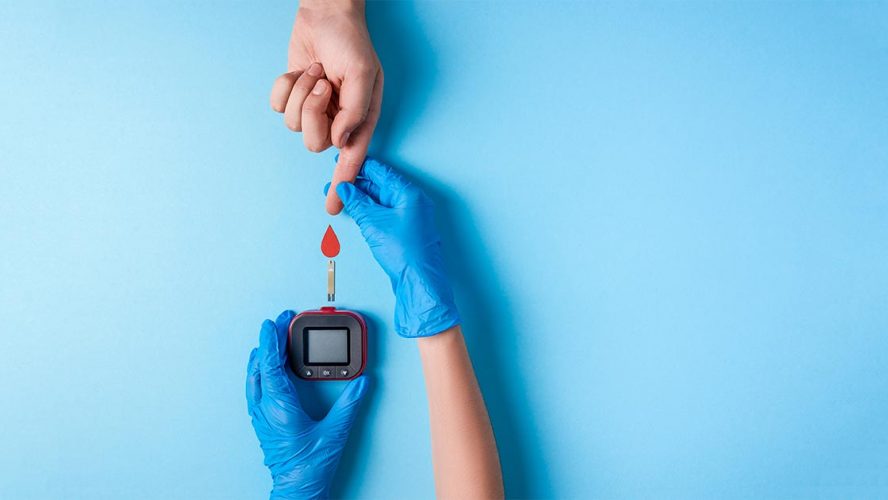 Verpleegster doet bloedtest. Hand met bloeddruppel en glucosemeter.