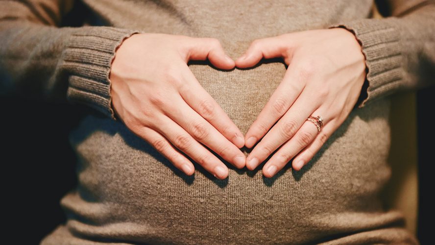 Zwangere vrouw legt handen op haar buik