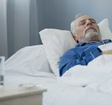 Oude man slaapt in ziekenhuisbed