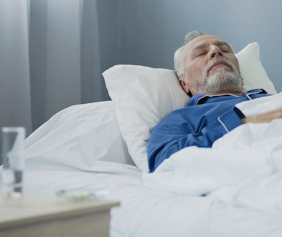 Oude man slaapt in ziekenhuisbed